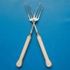 A pair of silver and ivory forks.
